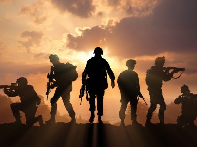 Six military silhouettes on sunset sky background